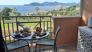 Un balcone con un tavolo apparecchiato per la colazione, con vista panoramica sul mare e sulle colline.