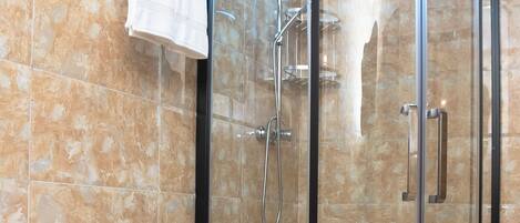 A bathroom with a toilet, a glass shower enclosure, and a towel rack.