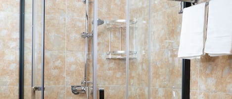 Eine Eckdusche mit Glastür, ein weißes Waschbecken und ein Handtuchhalter.