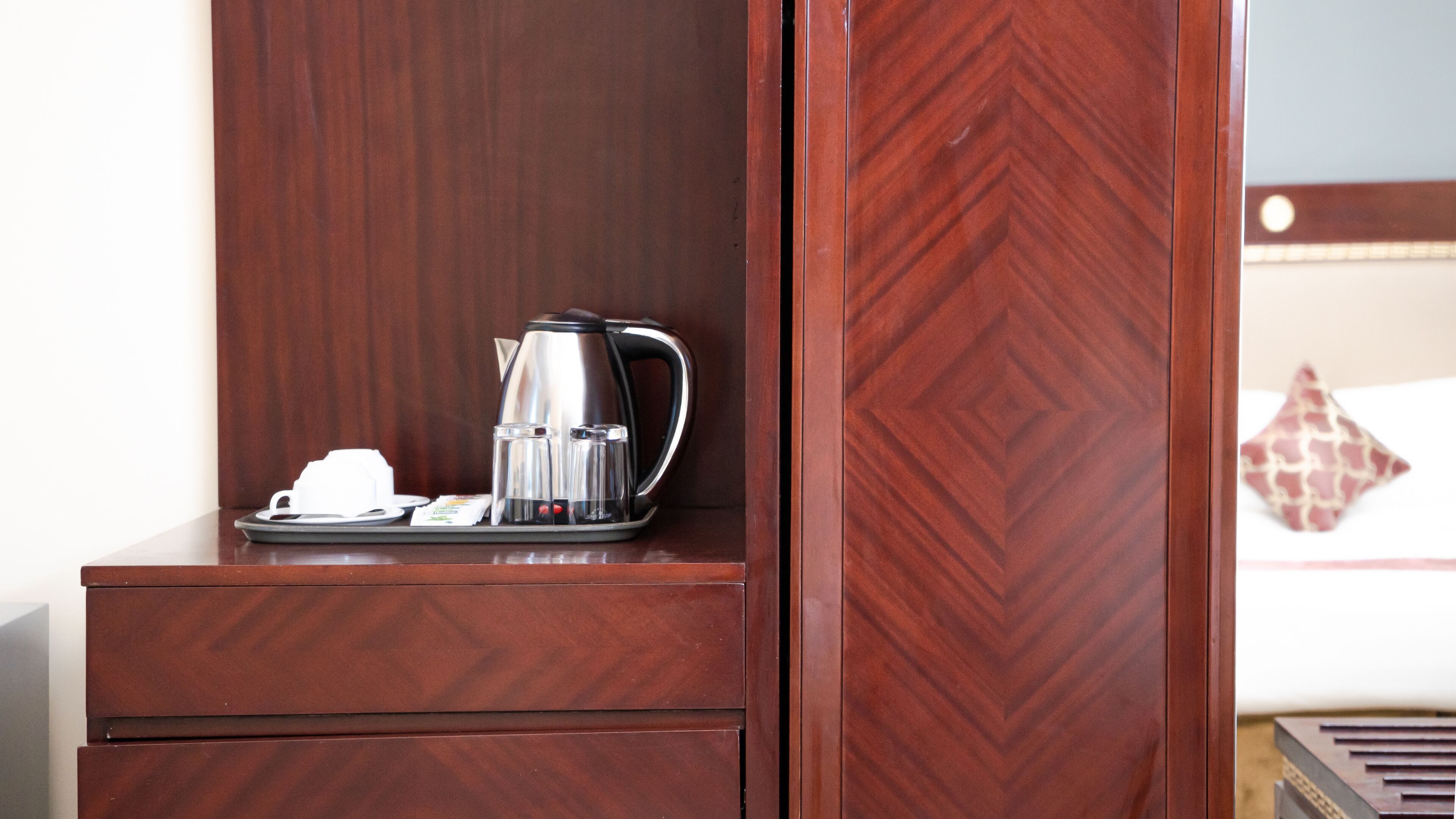 A wooden cabinet with a coffee maker and a tray of breakfast items.
