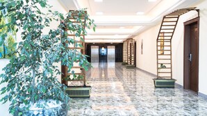 A hotel corridor with a marble floor, wooden staircases, and a large potted plant. - Dabi Hotel & Apartments (Addis Ababa)
