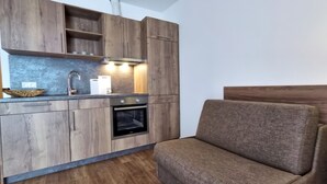 Moderni keittiö, jossa on puiset kaapit, sisäänrakennettu uuni ja harmaa työtaso.
