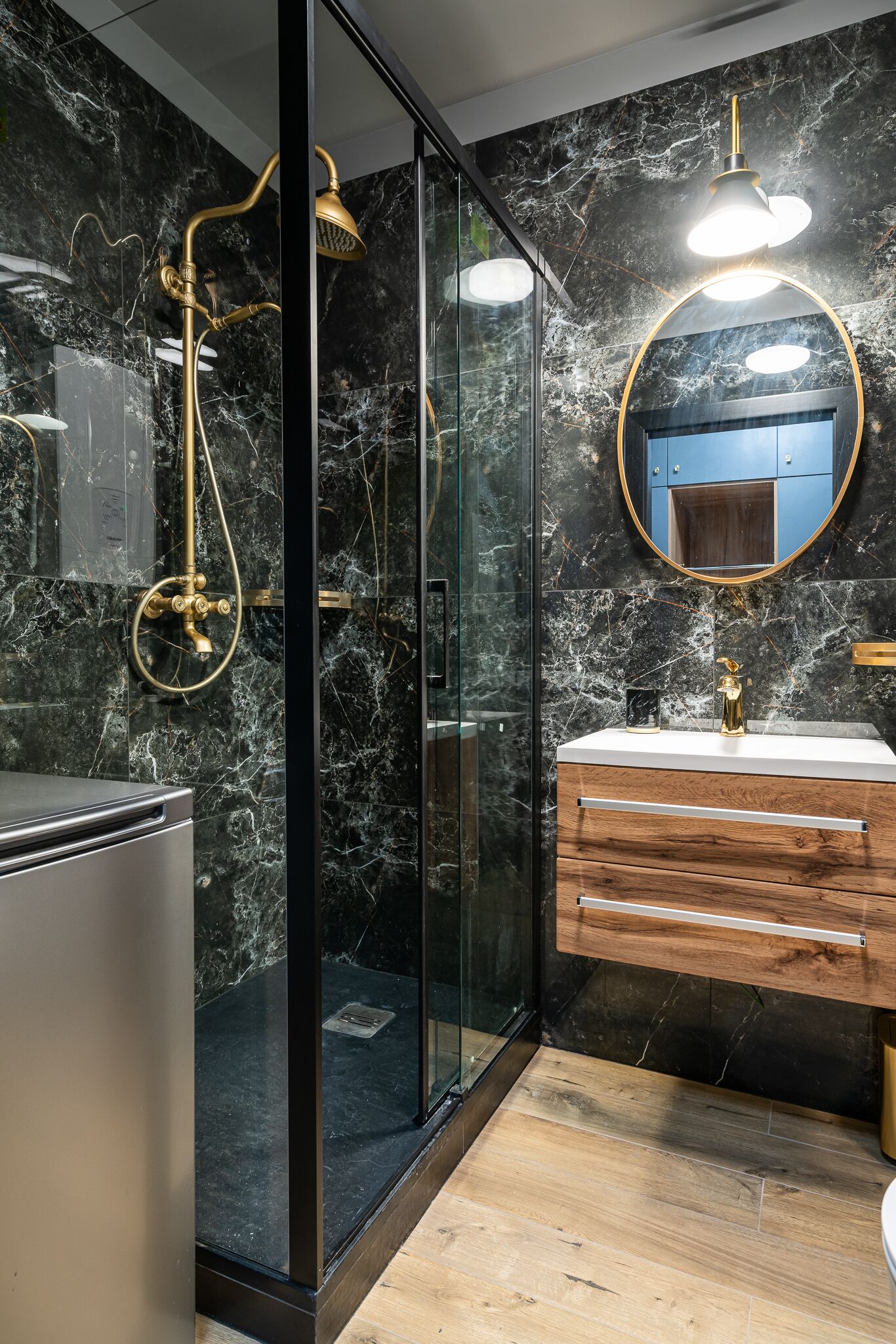 A modern bathroom with a glass-enclosed shower, a wooden vanity, and a marble backsplash.