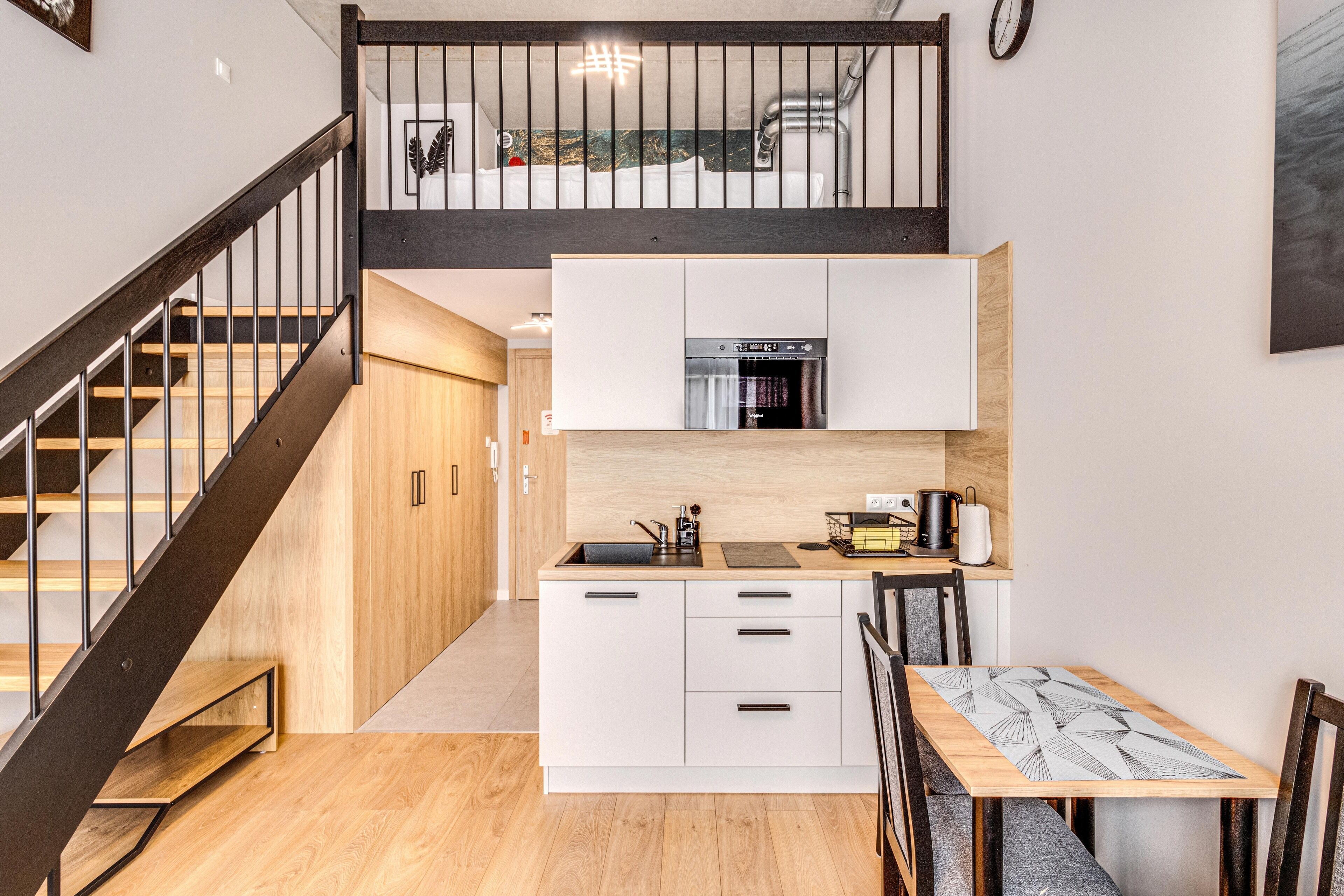 A modern kitchen with a built-in oven, white cabinets, and a wooden dining table.