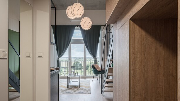 A modern interior with a staircase, a dining area with a view, and a large window with curtains. - RentPlanet - Apartamenty Zarembowicza (Wroclaw)