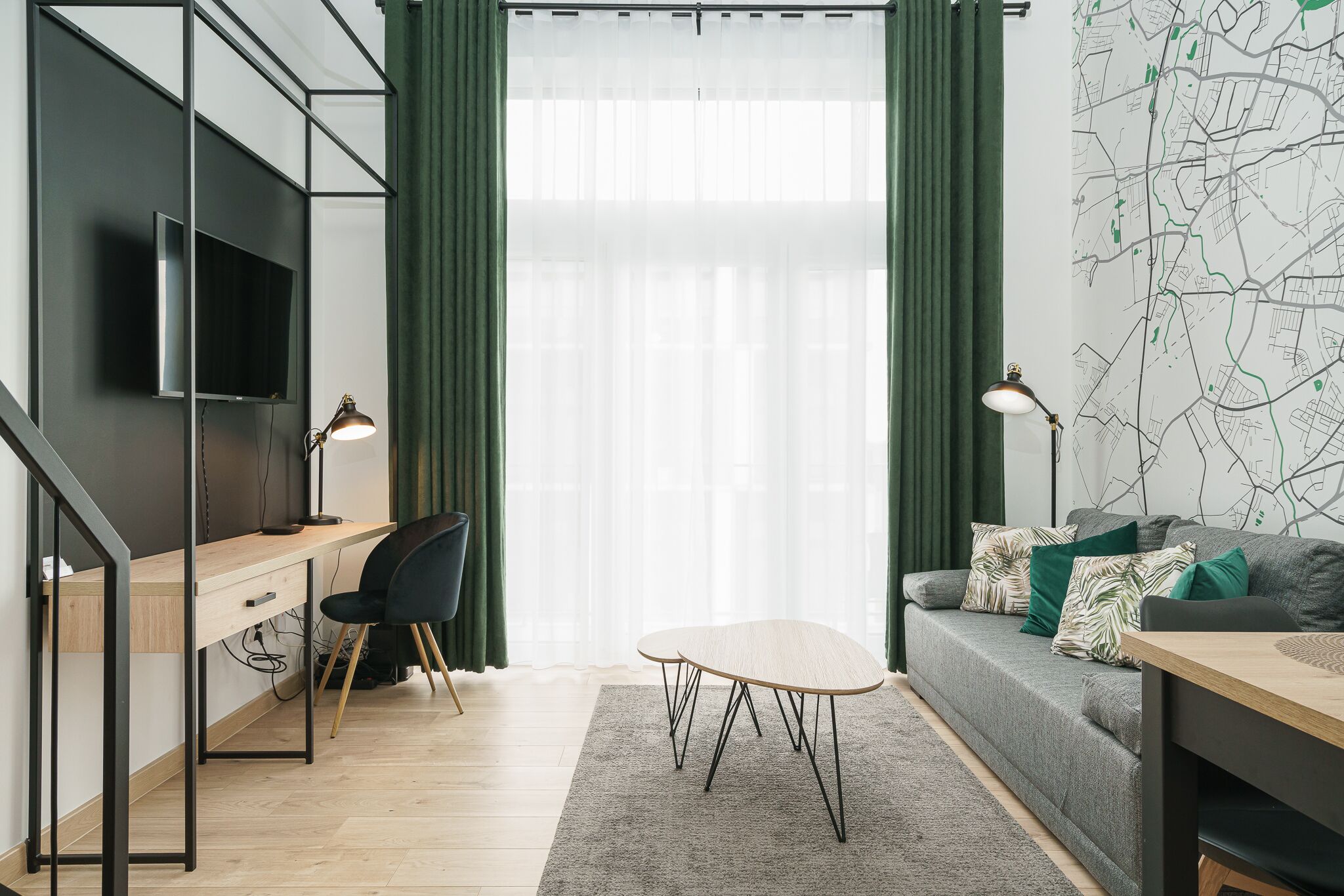 A modern living room with a desk, a sofa, and a TV mounted on the wall.