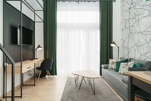 A modern living room with a desk, a sofa, and a TV mounted on the wall.