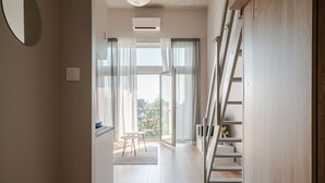 A modern interior with a staircase, a dining area with a table and chairs, and a view through large windows. - RentPlanet - Apartamenty Zarembowicza (Wroclaw)