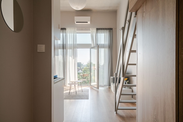 A modern interior with a staircase, a dining area with a table and chairs, and a view through large windows. - RentPlanet - Apartamenty Zarembowicza (Wroclaw)