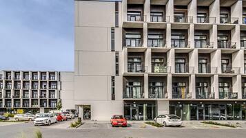 Un edificio moderno de varios pisos con un estacionamiento al frente.