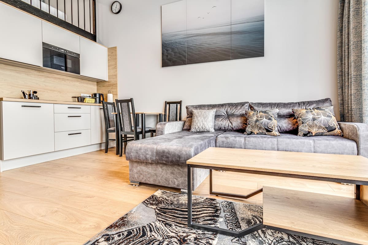 A modern living room with a grey sofa, wooden coffee table, and patterned rug.
