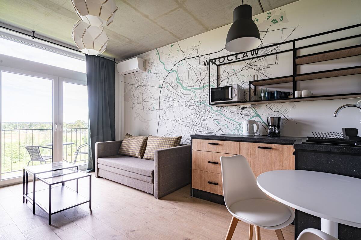 A modern apartment with a kitchenette, a dining area, and a balcony with a view.