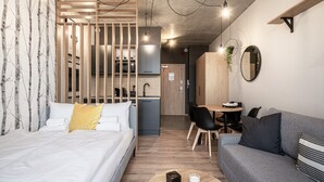 A modern hotel room with a bed, a sofa, a dining area, and a kitchen. - RentPlanet - Apartamenty Zarembowicza (Wroclaw)