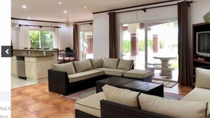 A spacious living room with a sectional sofa, a coffee table, and a television on a wooden stand.