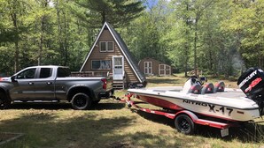 A cabin with a small deck and a boat trailer attached to a pickup truck.