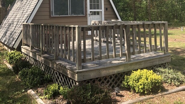 A small, single-story cabin with a wooden deck and a door.