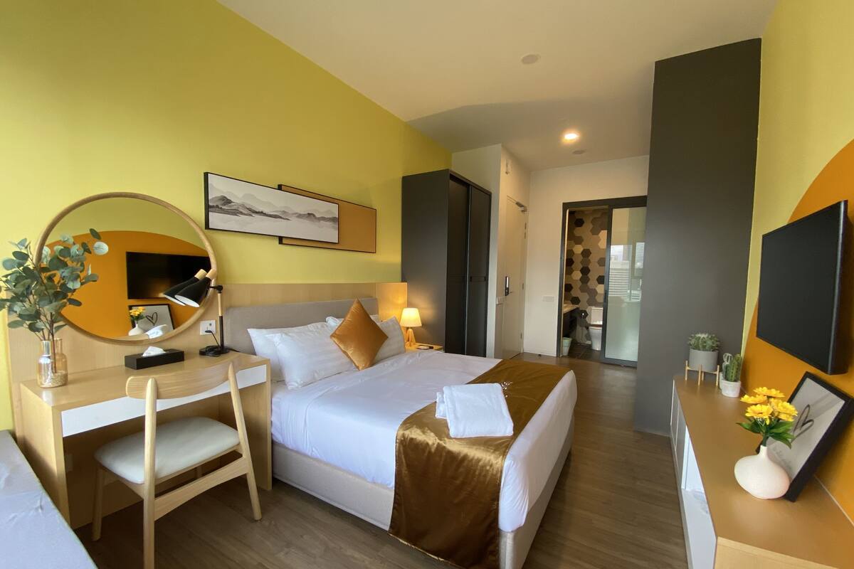 Una habitación de hotel con cama, escritorio, silla y espejo.