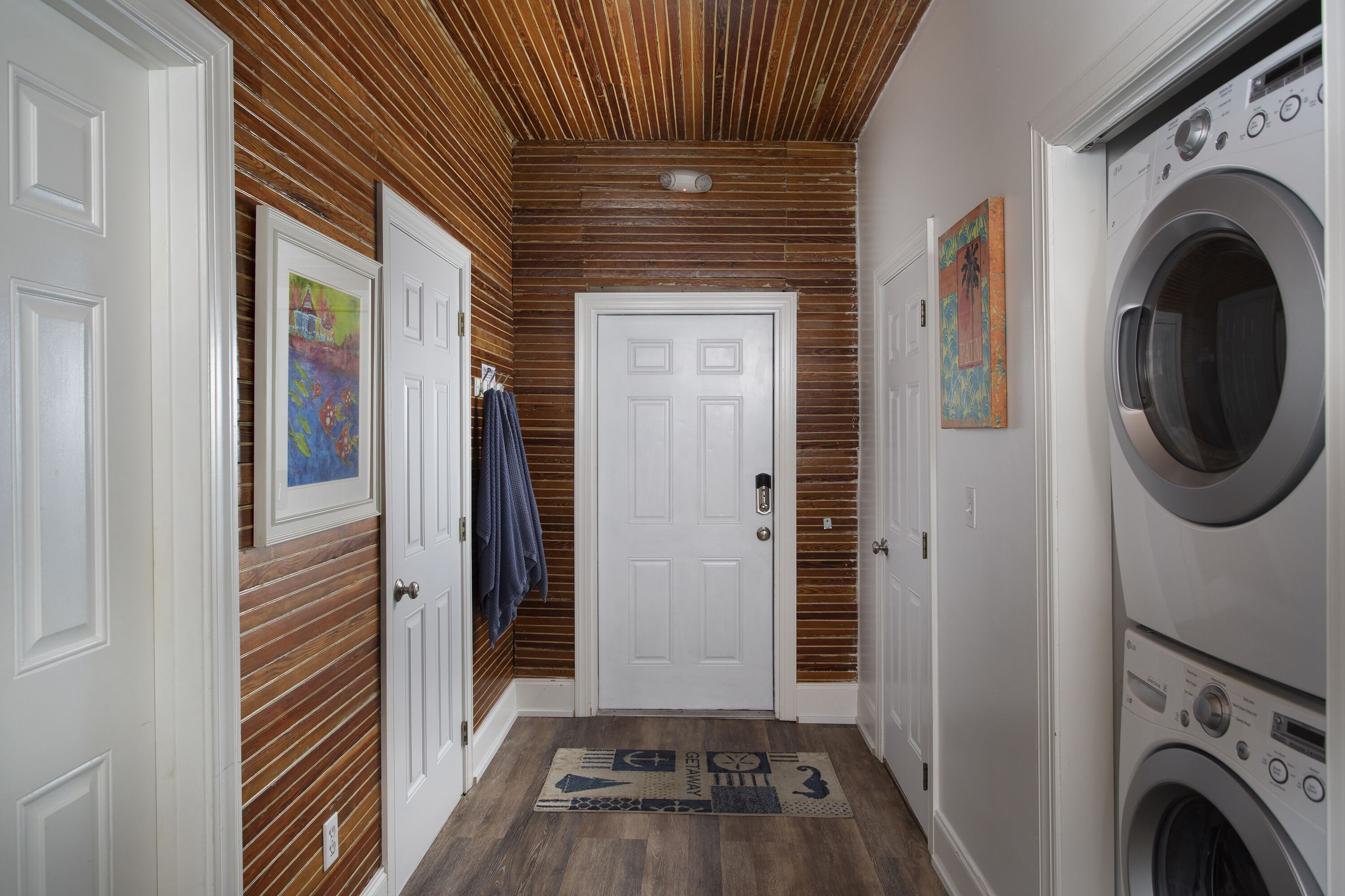 A laundry room with a washing machine, a door with a handle, and a wooden wall.