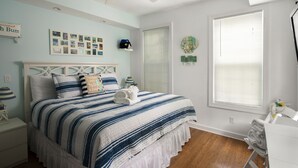 A bedroom with a bed, a ceiling fan, a window with blinds, and a wall with framed photos and decorations. - Bimini suite-3 bedroom 3 bath, a block off Duval St w/pool, parking (Key West)