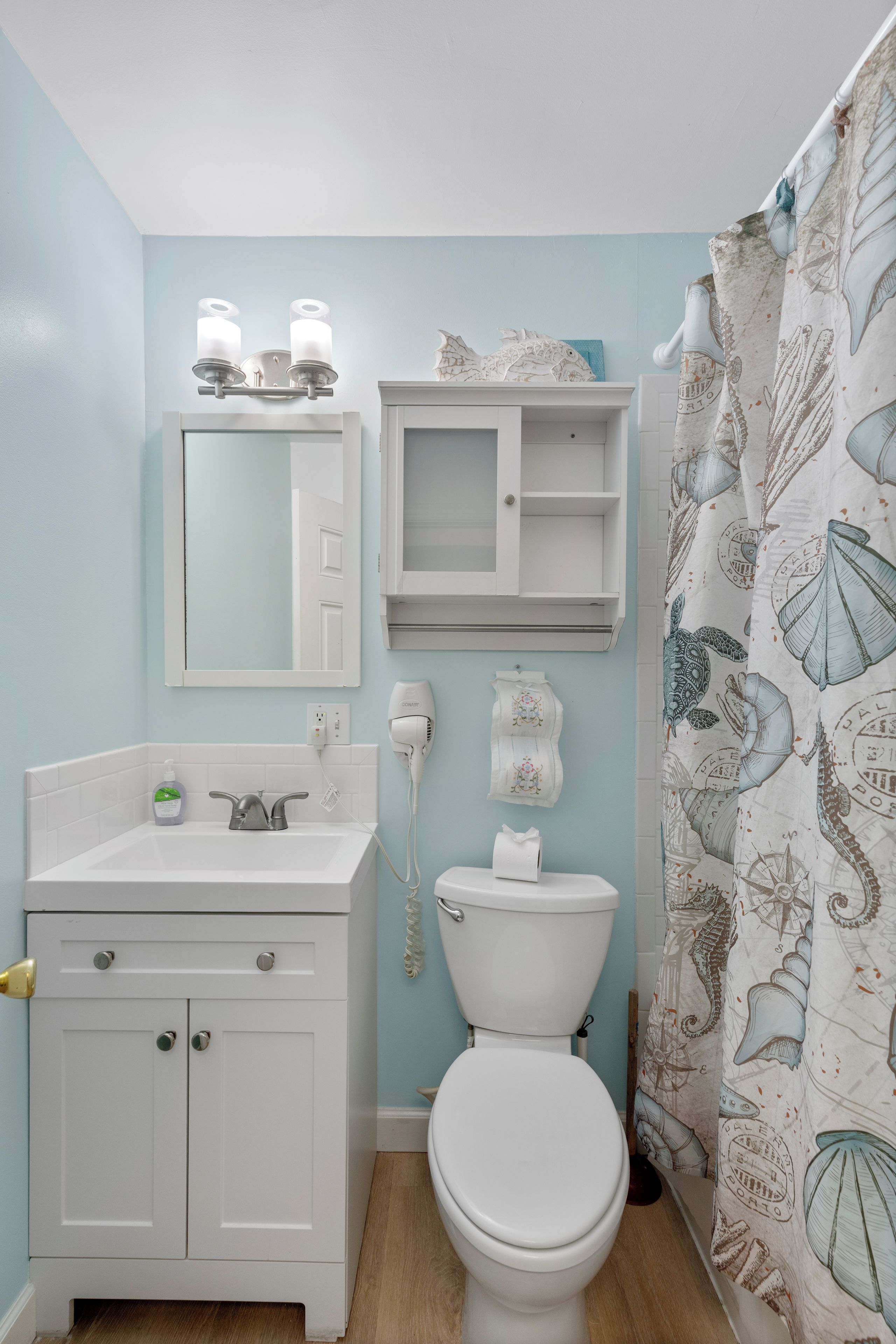 A bathroom with a toilet, sink, and mirror.