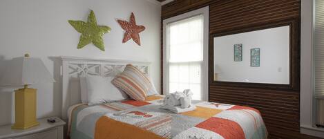Une chambre à coucher avec un lit, une table de chevet, une lampe et des étoiles de mer décoratives accrochées au mur.
