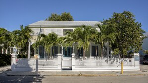 A two-story house with a white picket fence, palm trees, and a clear blue sky. - Paradise Island suite-2 bedroom 1 bath, a block off Duval St w/pool, parking (Key West)
