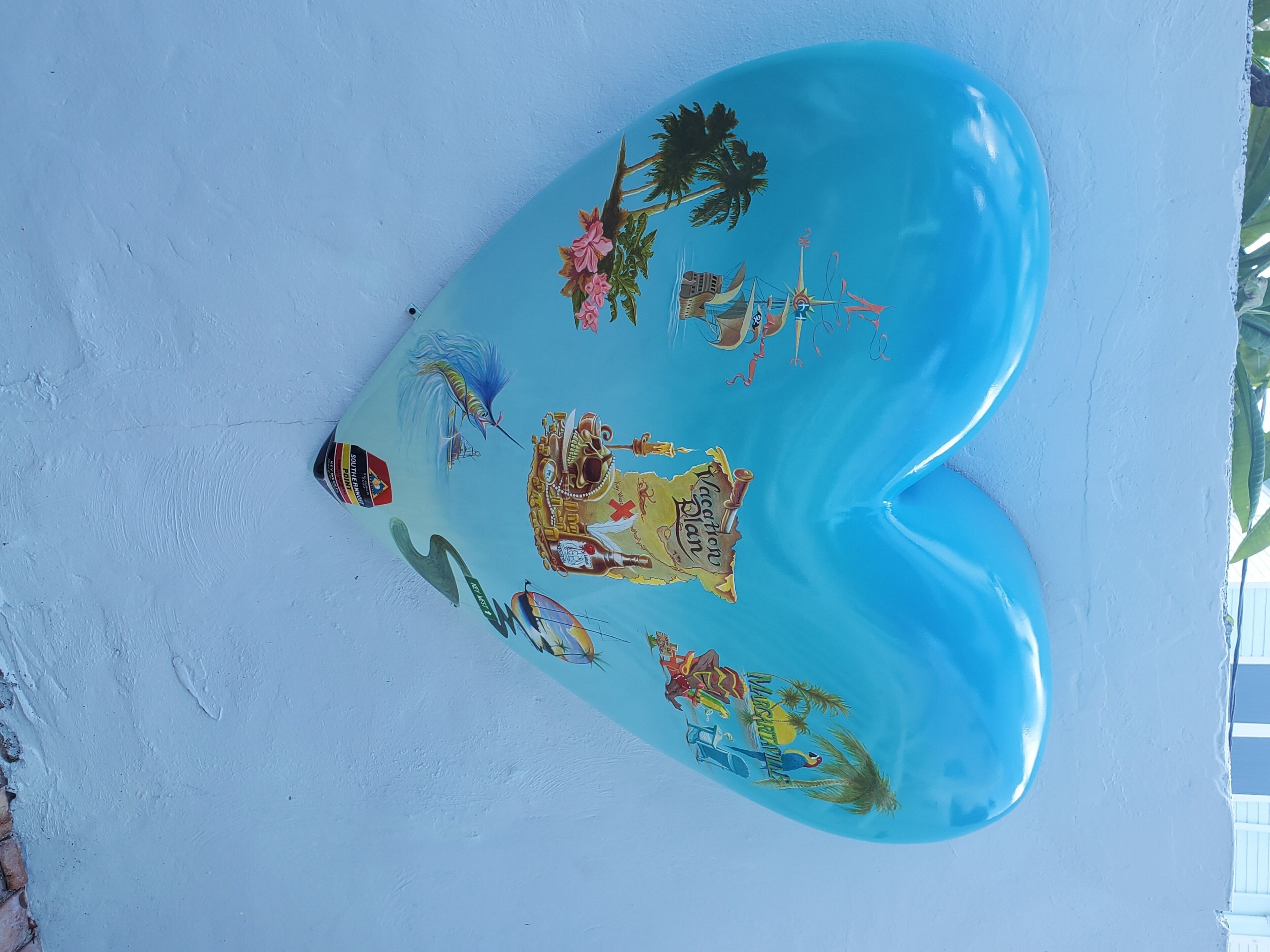 A heart-shaped object with various illustrations, including palm trees, a boat, and a treasure chest.