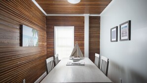 A dining area with a wooden paneled wall, a white ceiling, and a sailboat model on the table. - Paradise Island suite-2 bedroom 1 bath, a block off Duval St w/pool, parking (Key West)