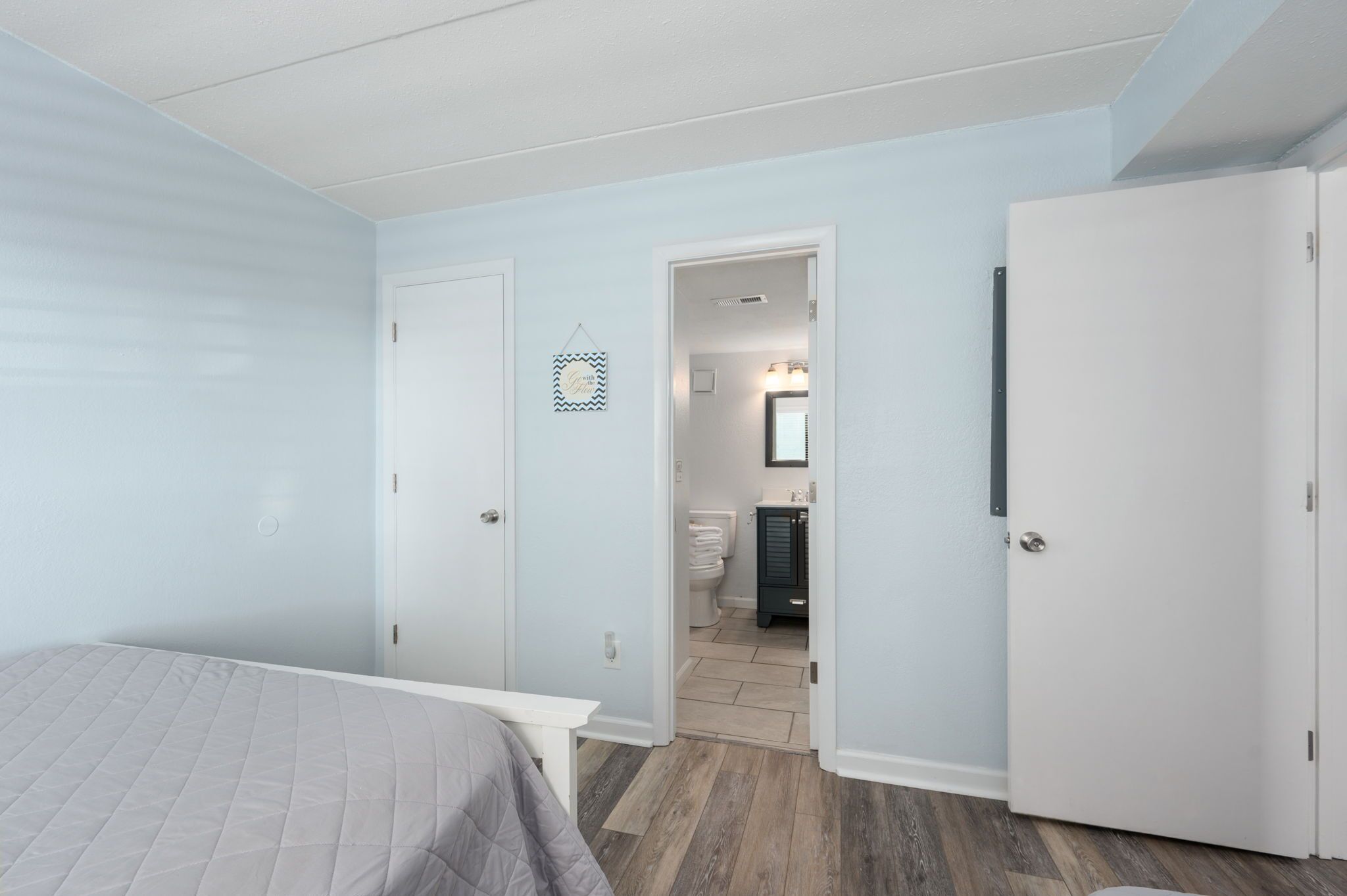 Ein Schlafzimmer mit einem Bett, einer Tür zu einem Badezimmer und einem Flur.
