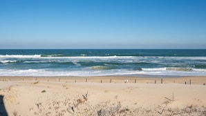 Une plage avec une clôture en bois et des vagues qui déferlent sur le rivage.