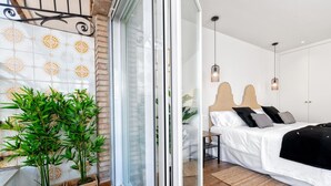 Ein Schlafzimmer mit Bett, Nachttischen und einem Fenster mit Blick auf Grünflächen.