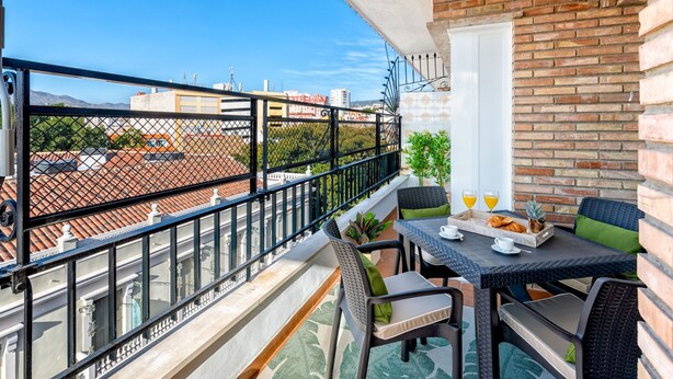 Ein Balkon mit Frühstückstisch, Blick auf die Stadtlandschaft und eine Ziegelwand.