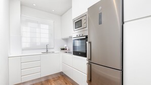 Eine moderne Küche mit weißen Schränken, einem Edelstahl-Kühlschrank, einer Mikrowelle und einem Backofen.