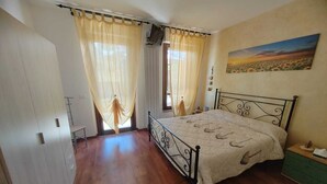 Ein Schlafzimmer mit Bett, Vorhängen, einem Gemälde und Holzboden.