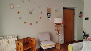 Ein Wohnzimmer mit einem Holzstuhl, einem kleinen Tisch, einer Couch und einer Wanduhr.