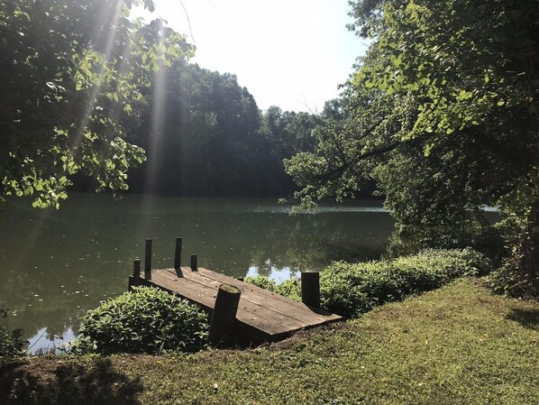 A wooden dock extending into a calm lake surrounded by lush greenery.