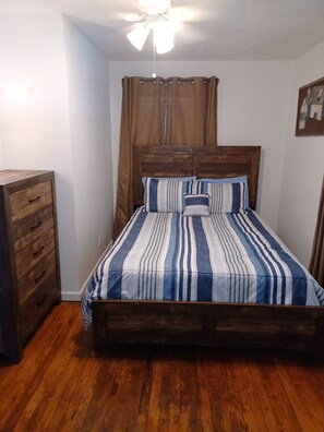 A bedroom with a wooden bed, a wooden dresser, and a ceiling fan.