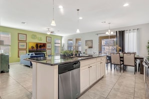 A modern kitchen with a dishwasher, dining area with chairs, and a view of the outdoors.