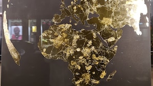 Une grande carte du monde, aux couleurs noir et or, était affichée sur un mur.