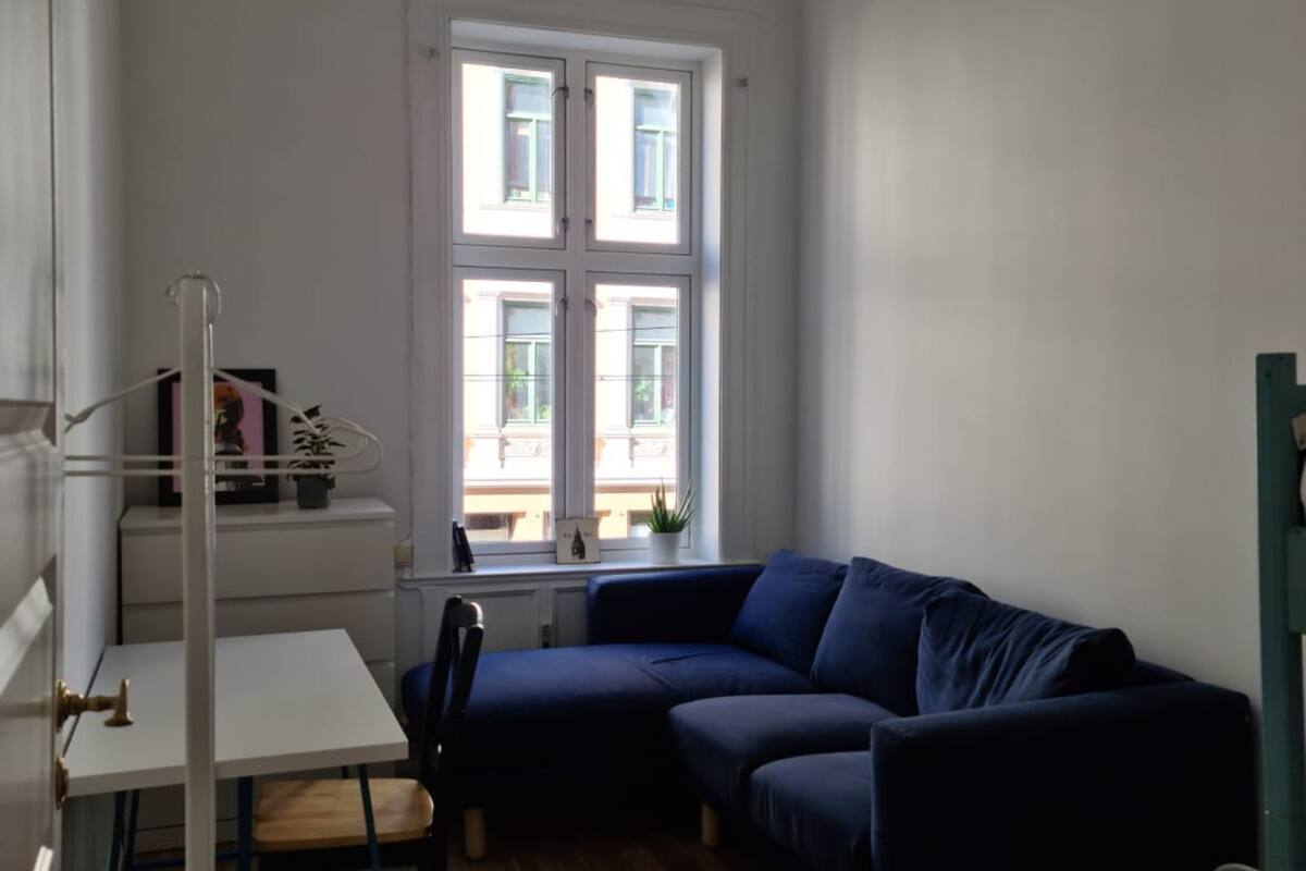A room with a dark blue sofa, a small white table, and a window with multiple panes.