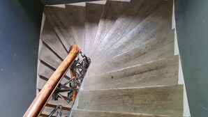 Un escalier en colimaçon avec une rampe en bois et des marches en métal.