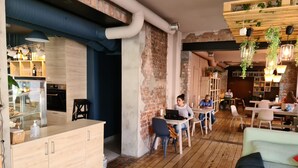 Un café chaleureux avec un plancher en bois, un mur en briques et un mélange de décorations modernes et rustiques.