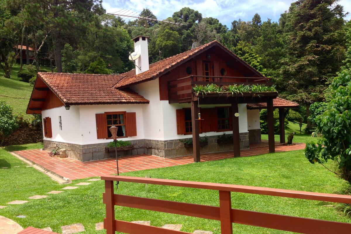A rustic house with a tiled roof, wooden shutters, and a stone foundation.