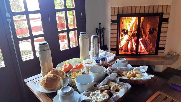 Une table de petit-déjeuner avec divers aliments et une cheminée en arrière-plan.