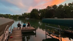 Une jetée en bois s’étendant sur une étendue d’eau calme, avec un ciel au coucher du soleil.