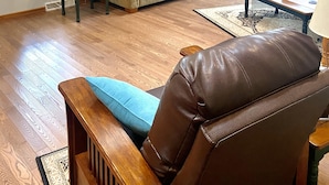 Un salon spacieux avec une grande fenêtre, un canapé, une table basse et un fauteuil en cuir.