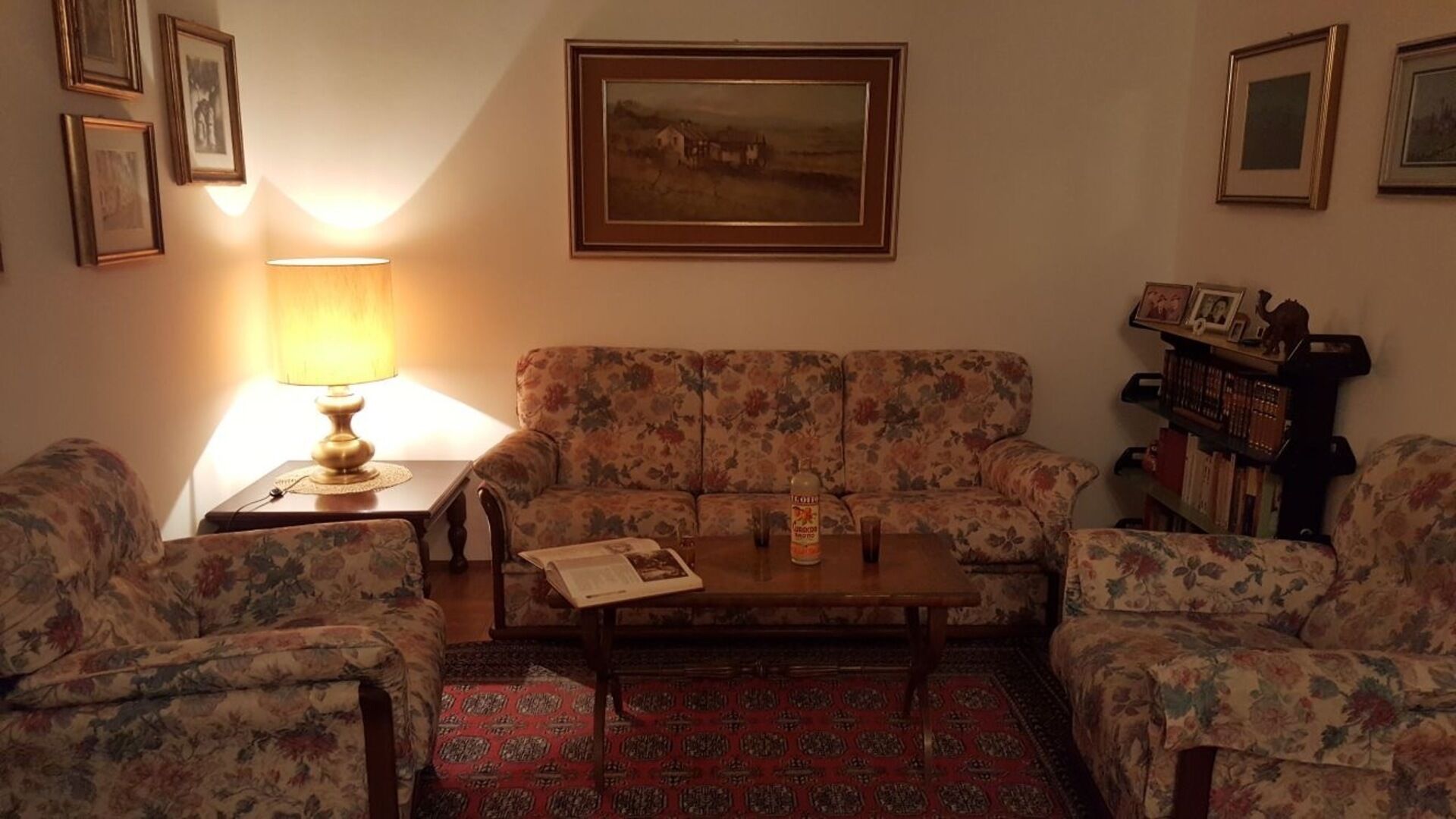 A living room with floral-patterned sofas, a wooden coffee table, and a lamp.