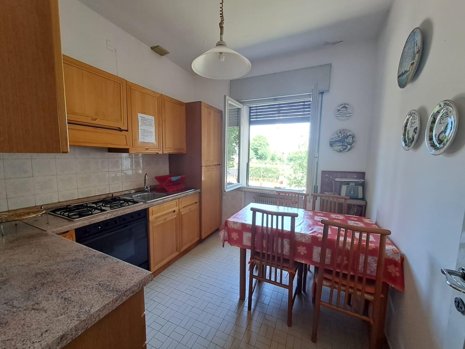Una cocina con armarios de madera, una estufa a gas y una mesa de comedor con sillas.