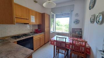 Una cocina con armarios de madera, una estufa a gas y una mesa de comedor con sillas.