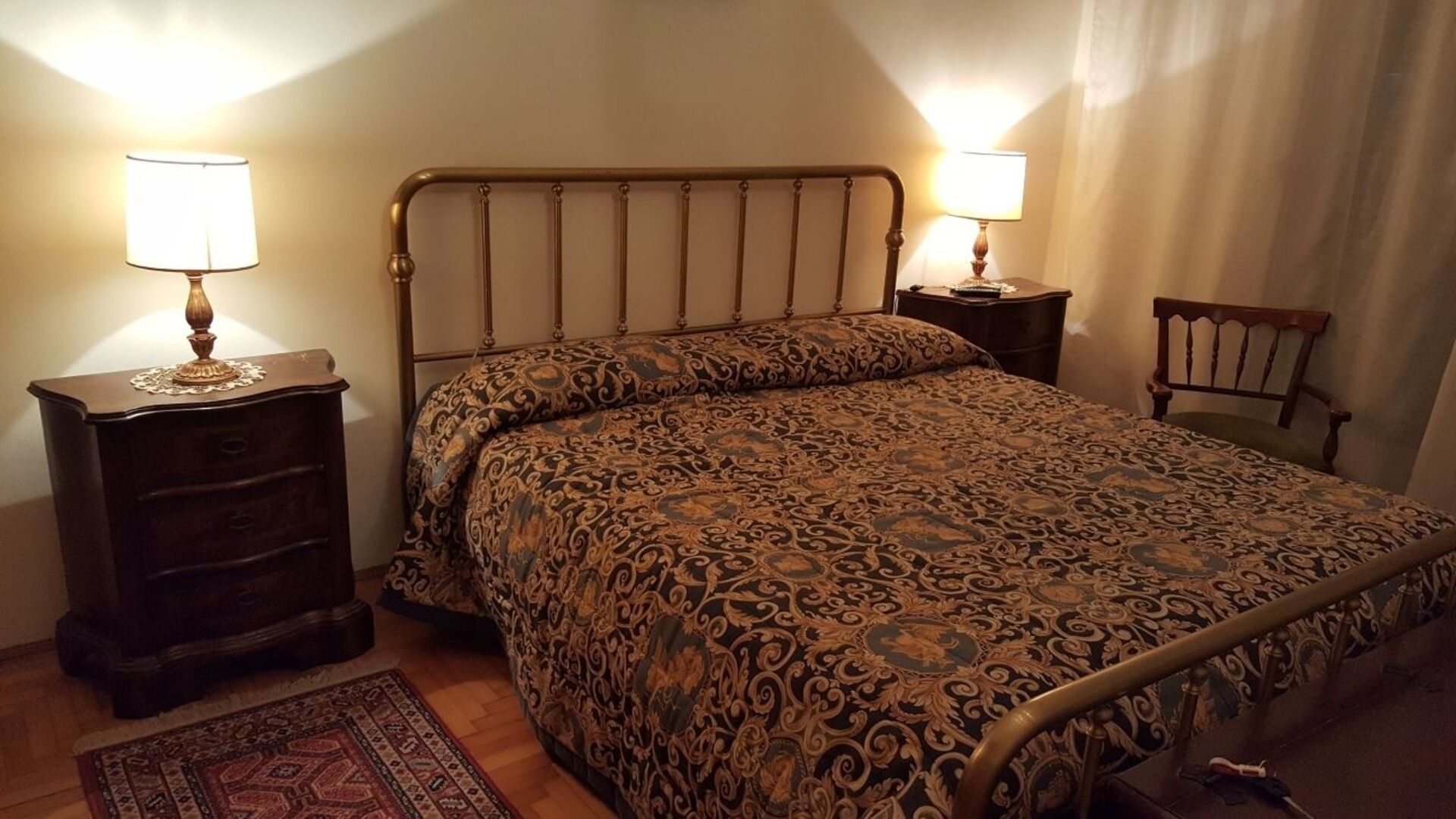 A bedroom with a bed, two nightstands, a chair, and a rug.